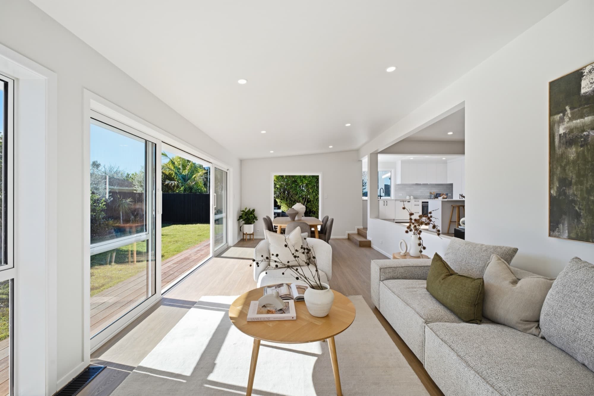 Living room opening to the deck through sliding doors, kitchen beyond