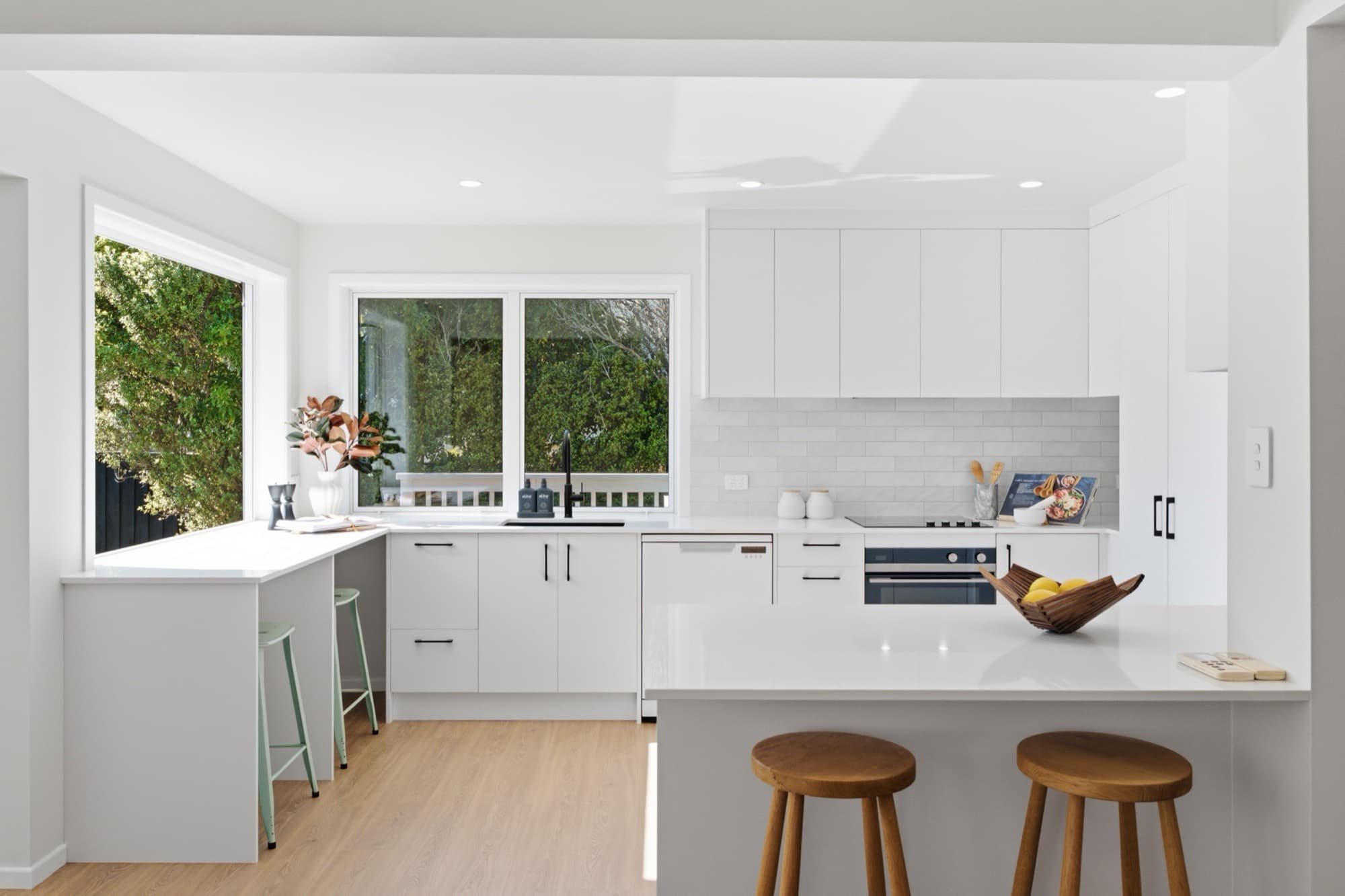 Kitchen with white cabinetry, a subway tile splashback, and timber stools