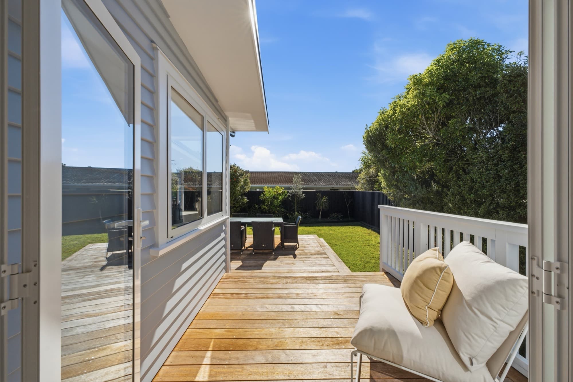 Deck in daylight with a daybed and outdoor dining beyond