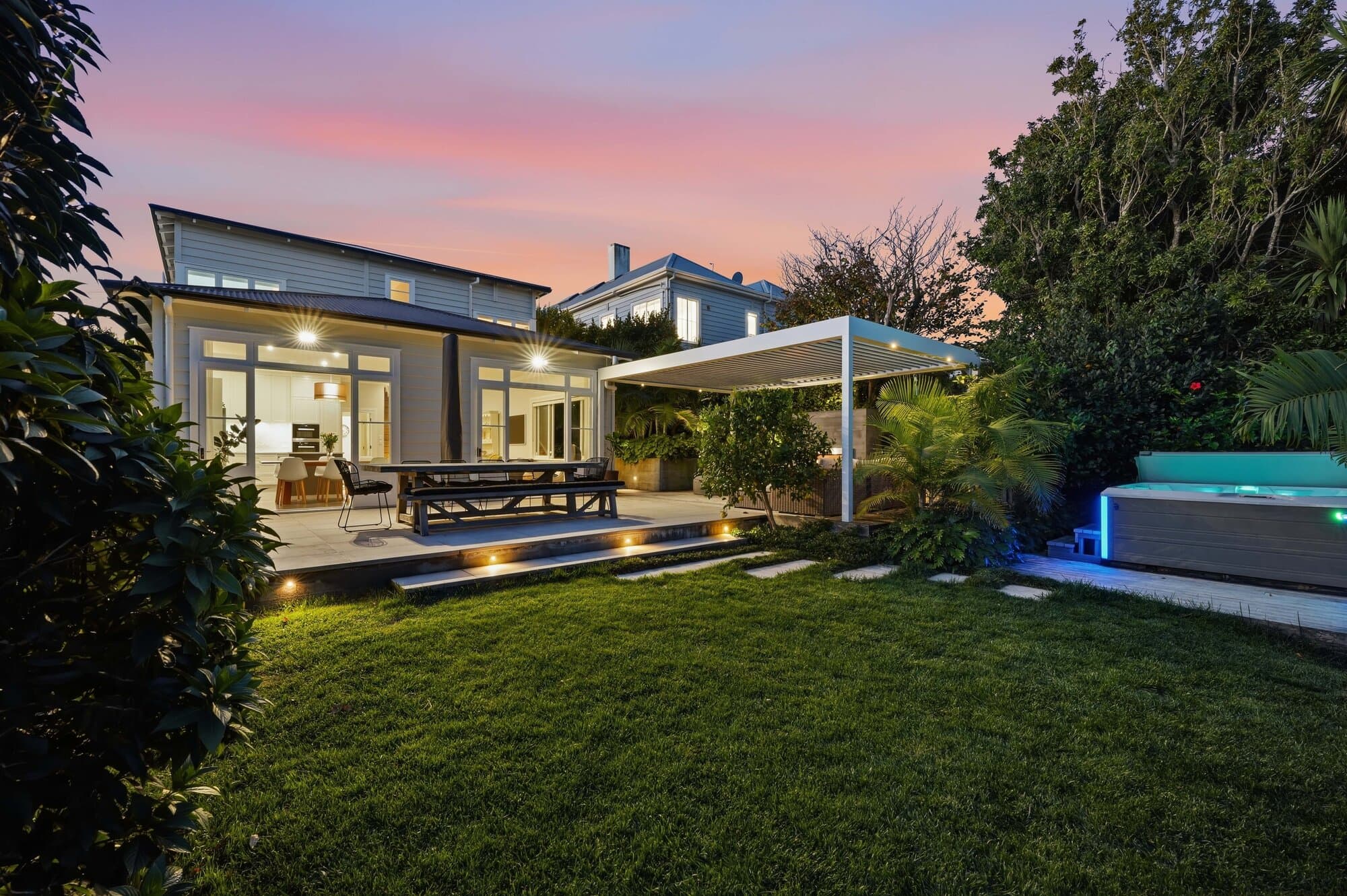 Exterior at twilight with pool and lit pergola